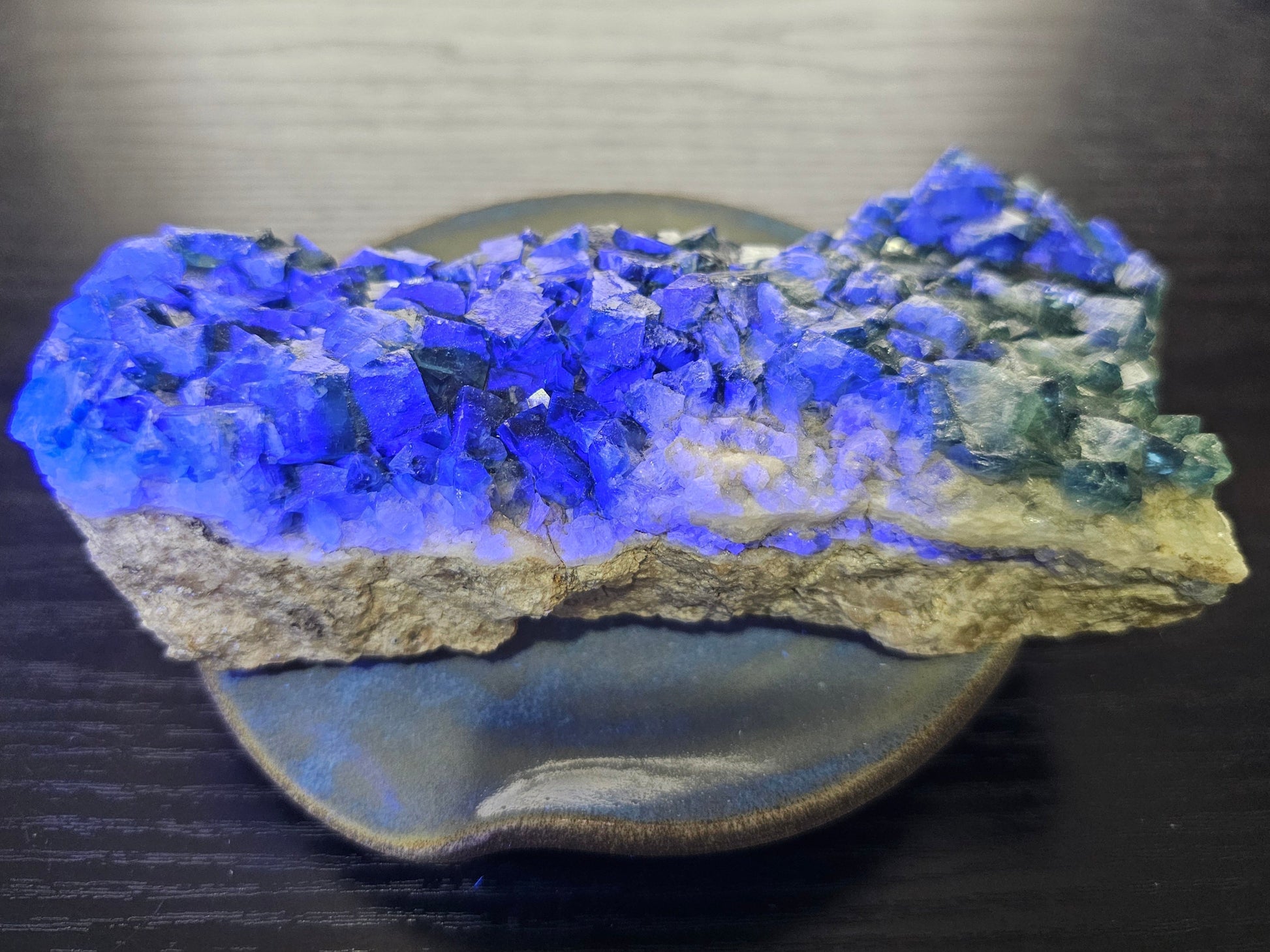 A 425g Madagascar Green Fluorite cube cluster displaying a vibrant, deep blue-purple fluorescence color change under a long-wave UV light source.
