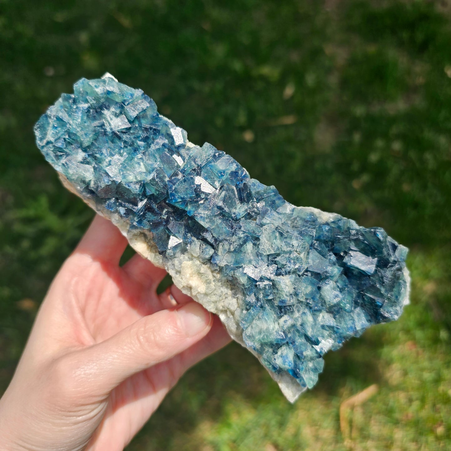 A 425g Madagascar Green Fluorite cube cluster displaying a vibrant, deep blue-purple fluorescence color change under a long-wave UV light source.