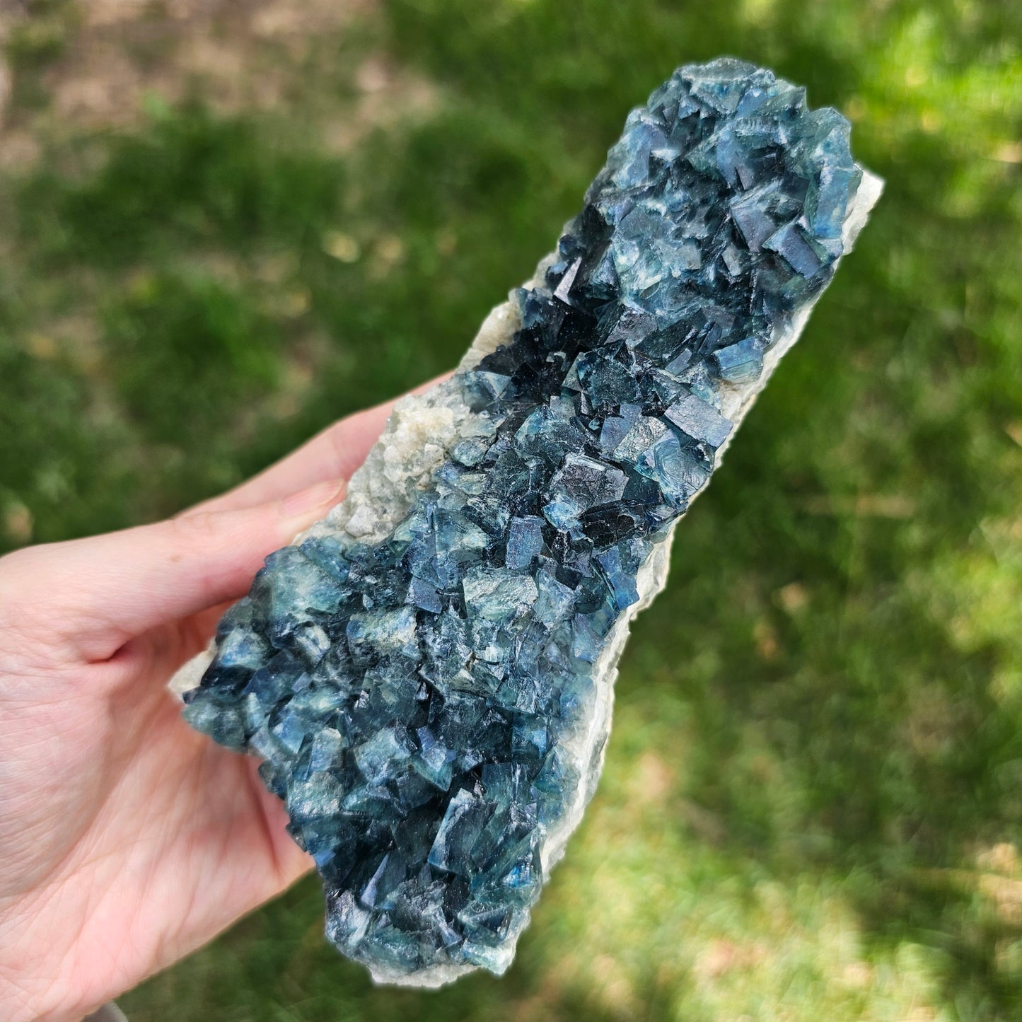 A 425g Madagascar Green Fluorite cube cluster displaying a vibrant, deep blue-purple fluorescence color change under a long-wave UV light source.