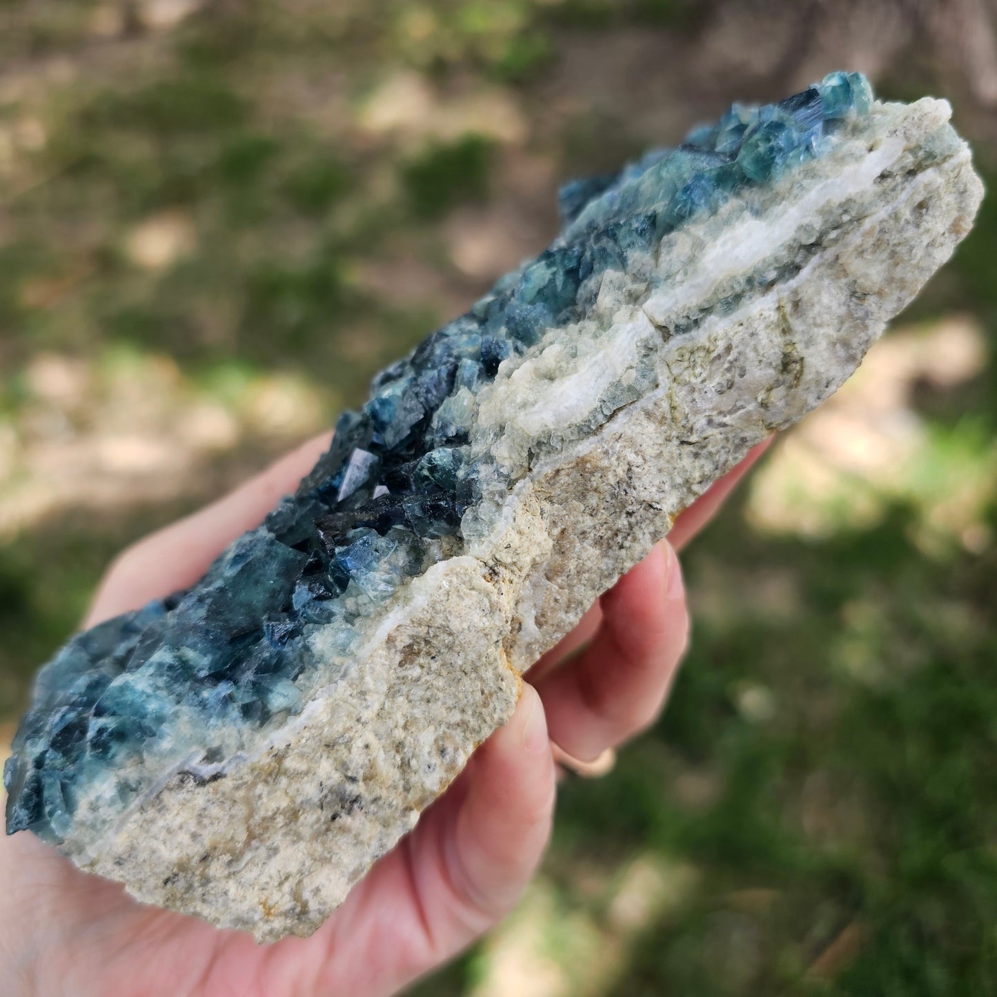 A 425g Madagascar Green Fluorite cube cluster displaying a vibrant, deep blue-purple fluorescence color change under a long-wave UV light source.