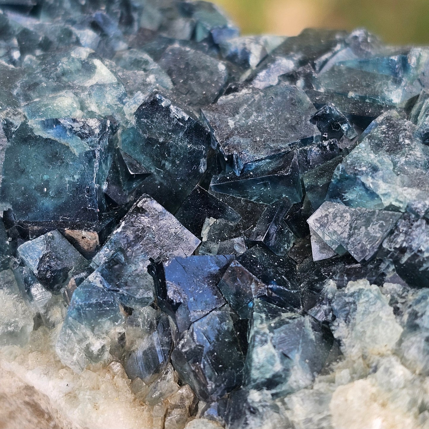 A 425g Madagascar Green Fluorite cube cluster displaying a vibrant, deep blue-purple fluorescence color change under a long-wave UV light source.
