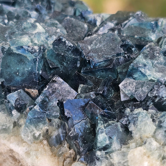 A 425g Madagascar Green Fluorite cube cluster displaying a vibrant, deep blue-purple fluorescence color change under a long-wave UV light source.