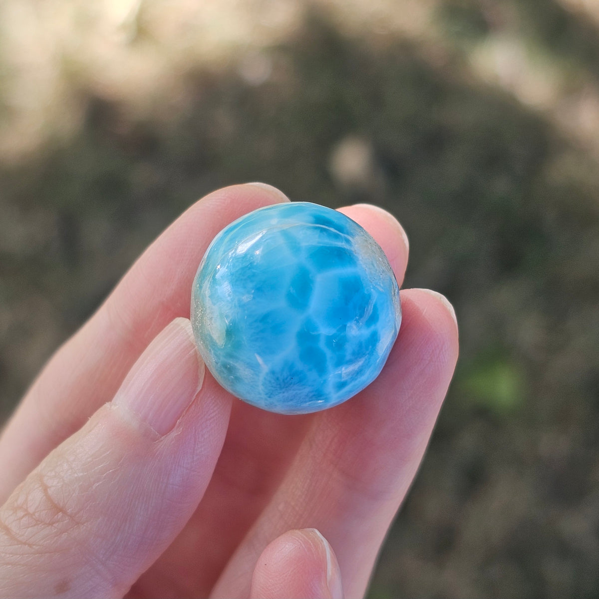 Front view of a 14.2g natural ocean-blue Larimar sphere with white wave patterns and light matrix inclusions.
