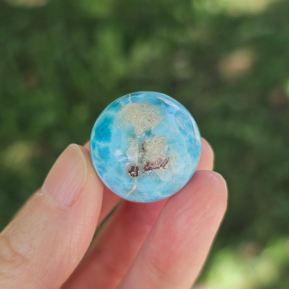 Front view of a 14.2g natural ocean-blue Larimar sphere with white wave patterns and light matrix inclusions.