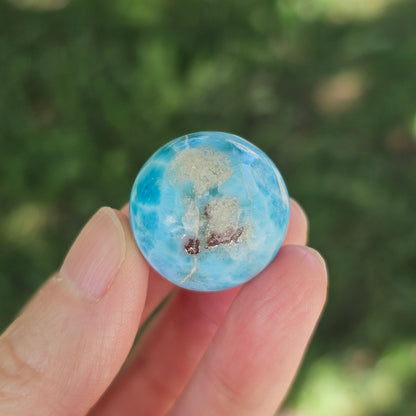 Front view of a 14.2g natural ocean-blue Larimar sphere with white wave patterns and light matrix inclusions.