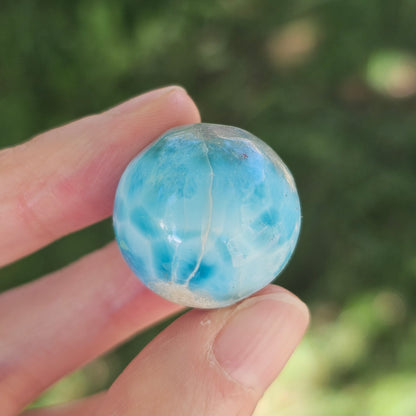 Front view of a 14.2g natural ocean-blue Larimar sphere with white wave patterns and light matrix inclusions.