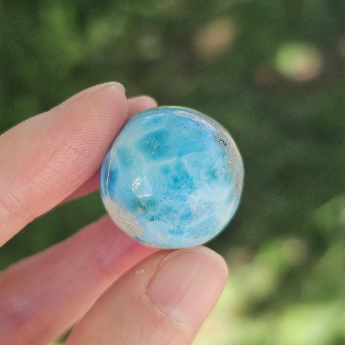Front view of a 14.2g natural ocean-blue Larimar sphere with white wave patterns and light matrix inclusions.