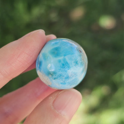 Front view of a 14.2g natural ocean-blue Larimar sphere with white wave patterns and light matrix inclusions.