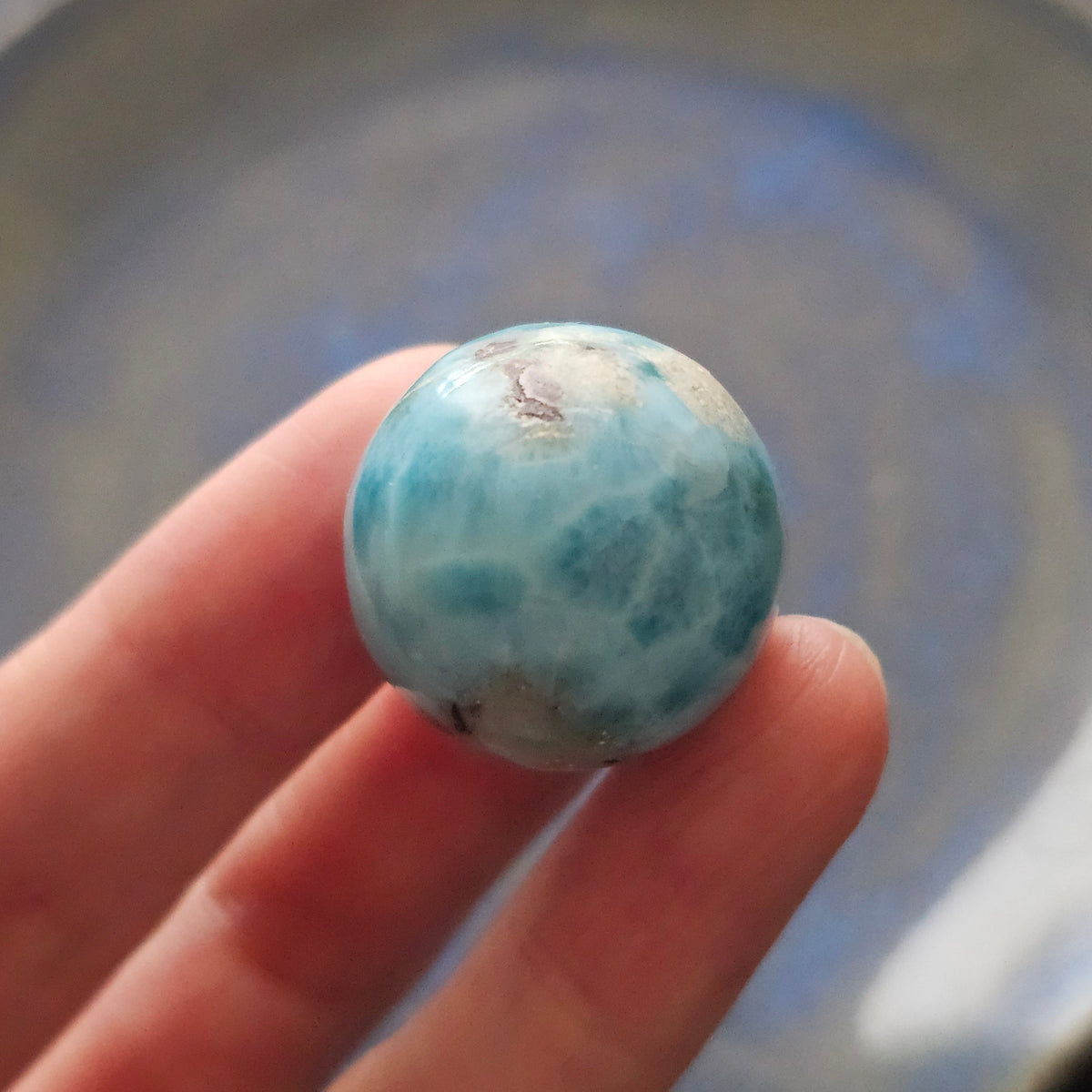 Front view of a 14.2g natural ocean-blue Larimar sphere with white wave patterns and light matrix inclusions.