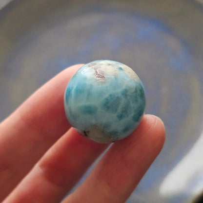 Front view of a 14.2g natural ocean-blue Larimar sphere with white wave patterns and light matrix inclusions.