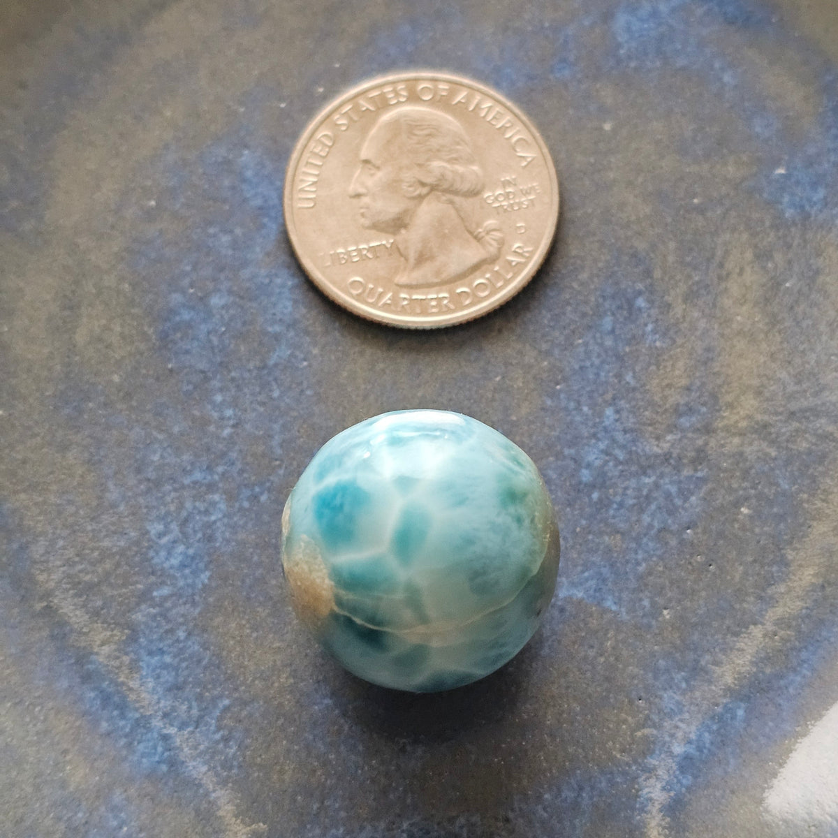 Natural 14.2g Larimar sphere placed next to a US quarter coin for size and scale comparison.