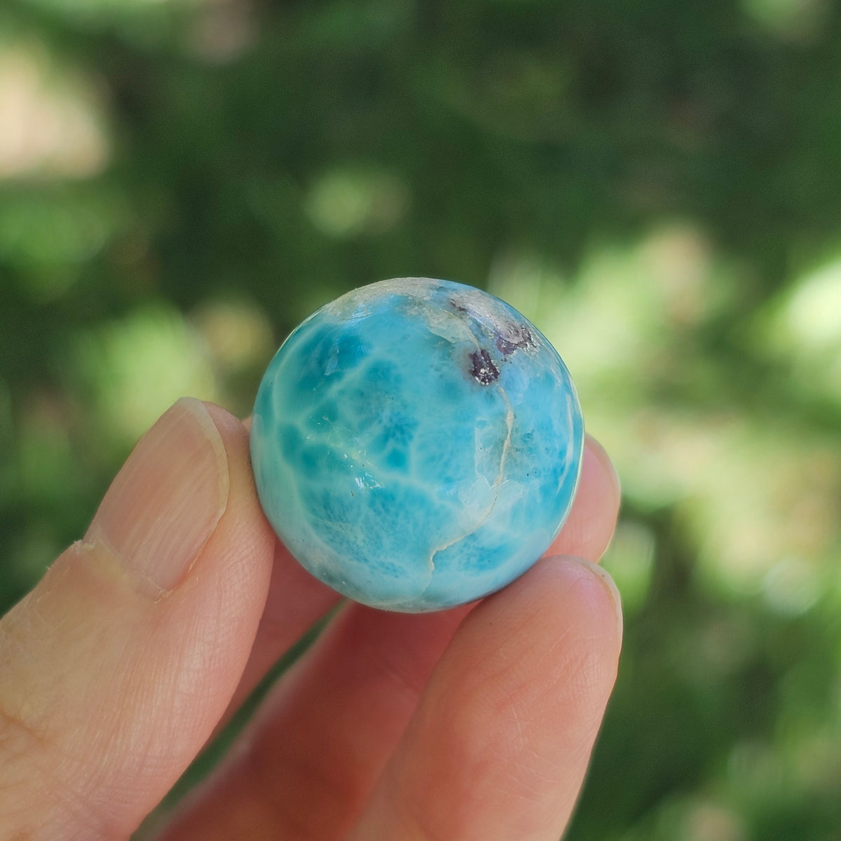 Front view of a 14.2g natural ocean-blue Larimar sphere with white wave patterns and light matrix inclusions.