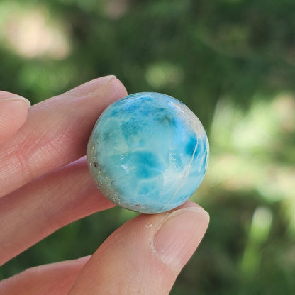 Front view of a 14.2g natural ocean-blue Larimar sphere with white wave patterns and light matrix inclusions.