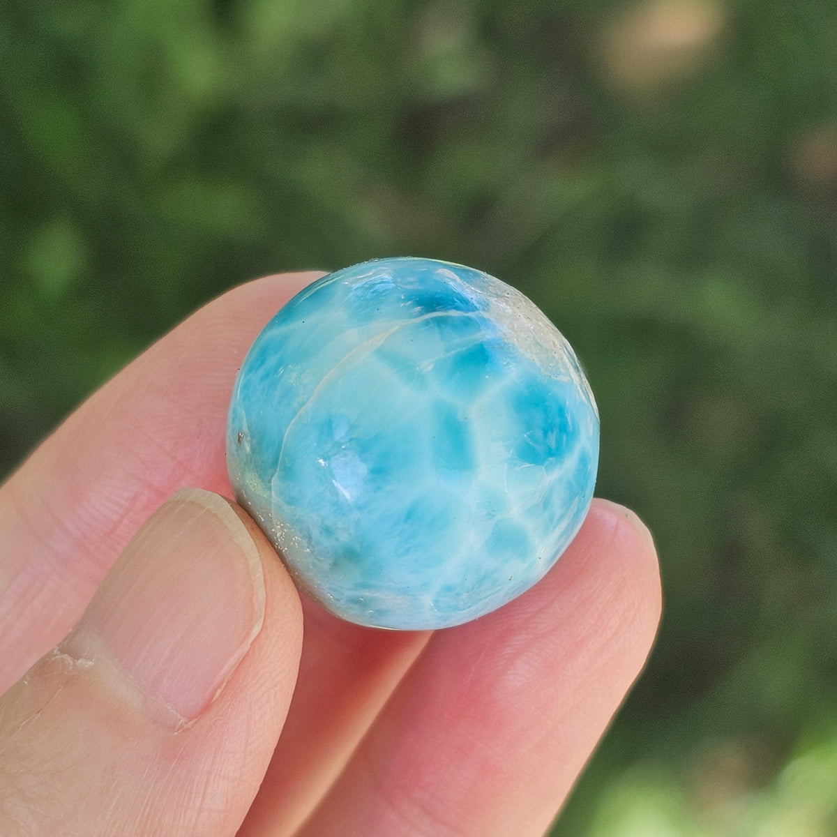 Front view of a 14.2g natural ocean-blue Larimar sphere with white wave patterns and light matrix inclusions.