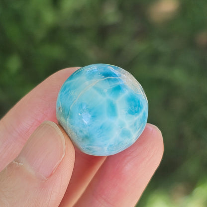 Front view of a 14.2g natural ocean-blue Larimar sphere with white wave patterns and light matrix inclusions.