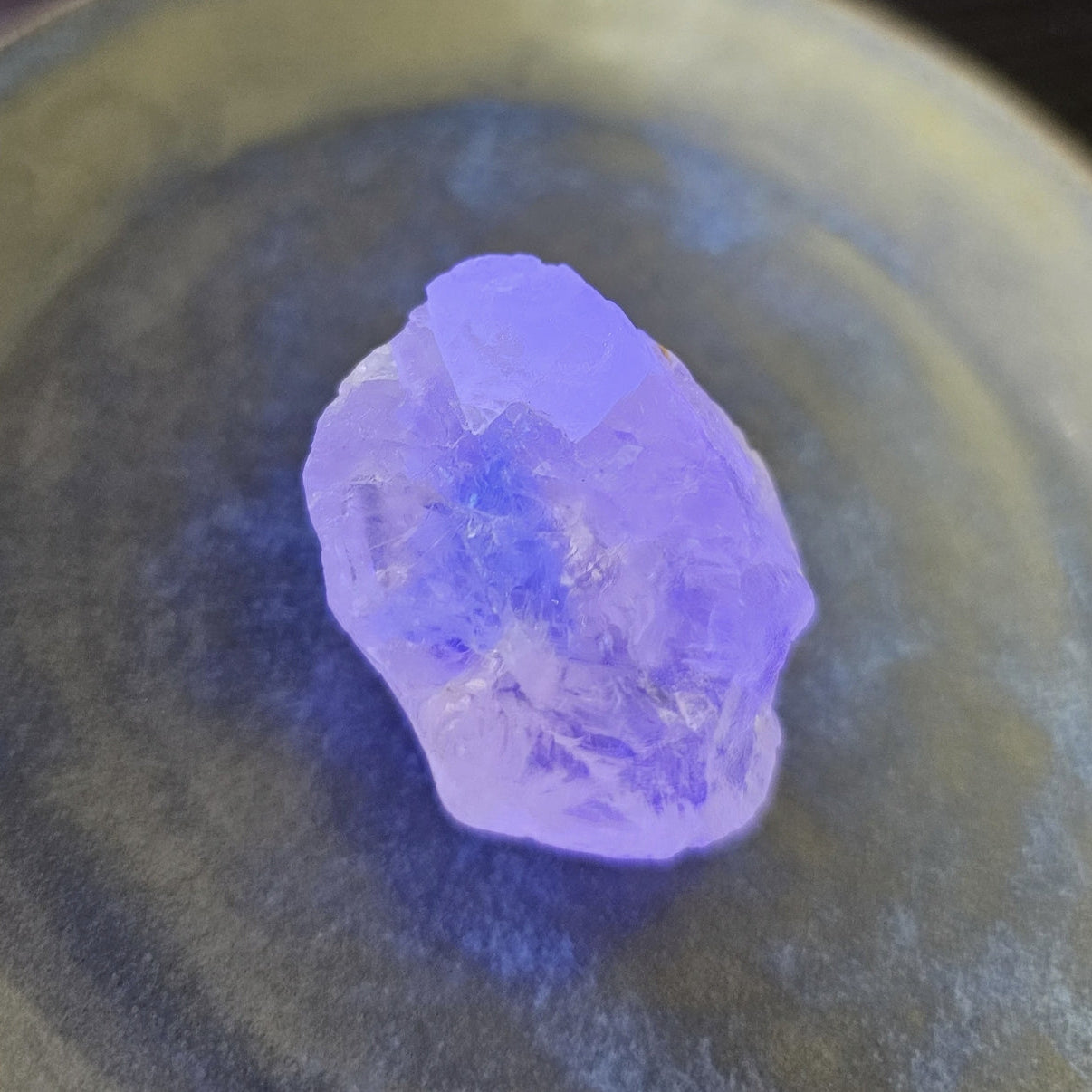 Unpolished purple crystal on a dark surface