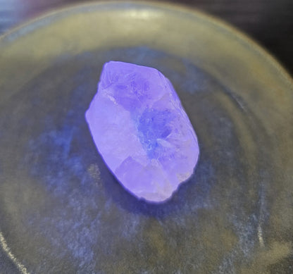 Purple crystal on a dark reflective surface