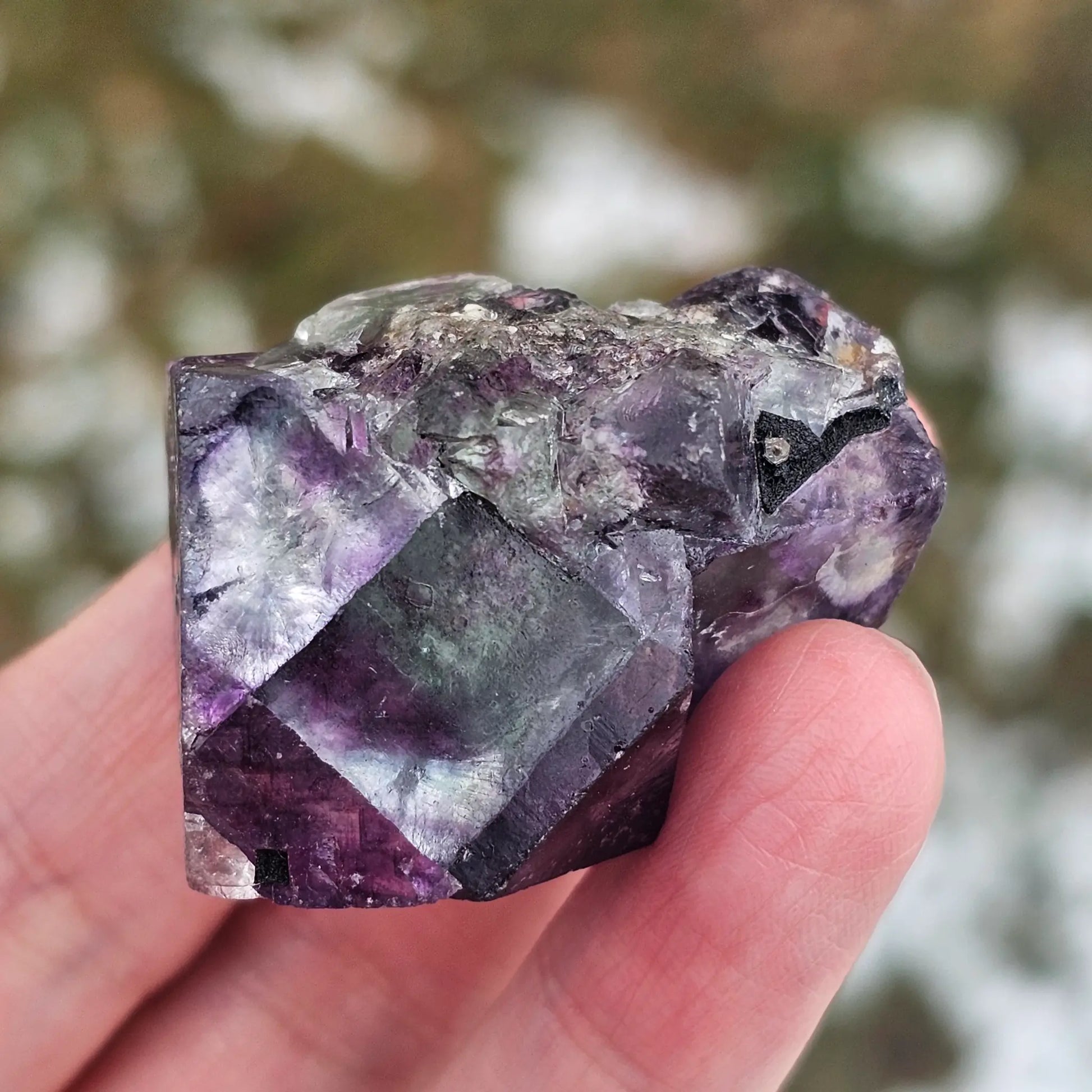 Close-up of an Alien Eye Fluorite specimen from Erongo, Namibia, showing a 1.5 inch twin crystal with deep green and purple aurora-like phantom zones.