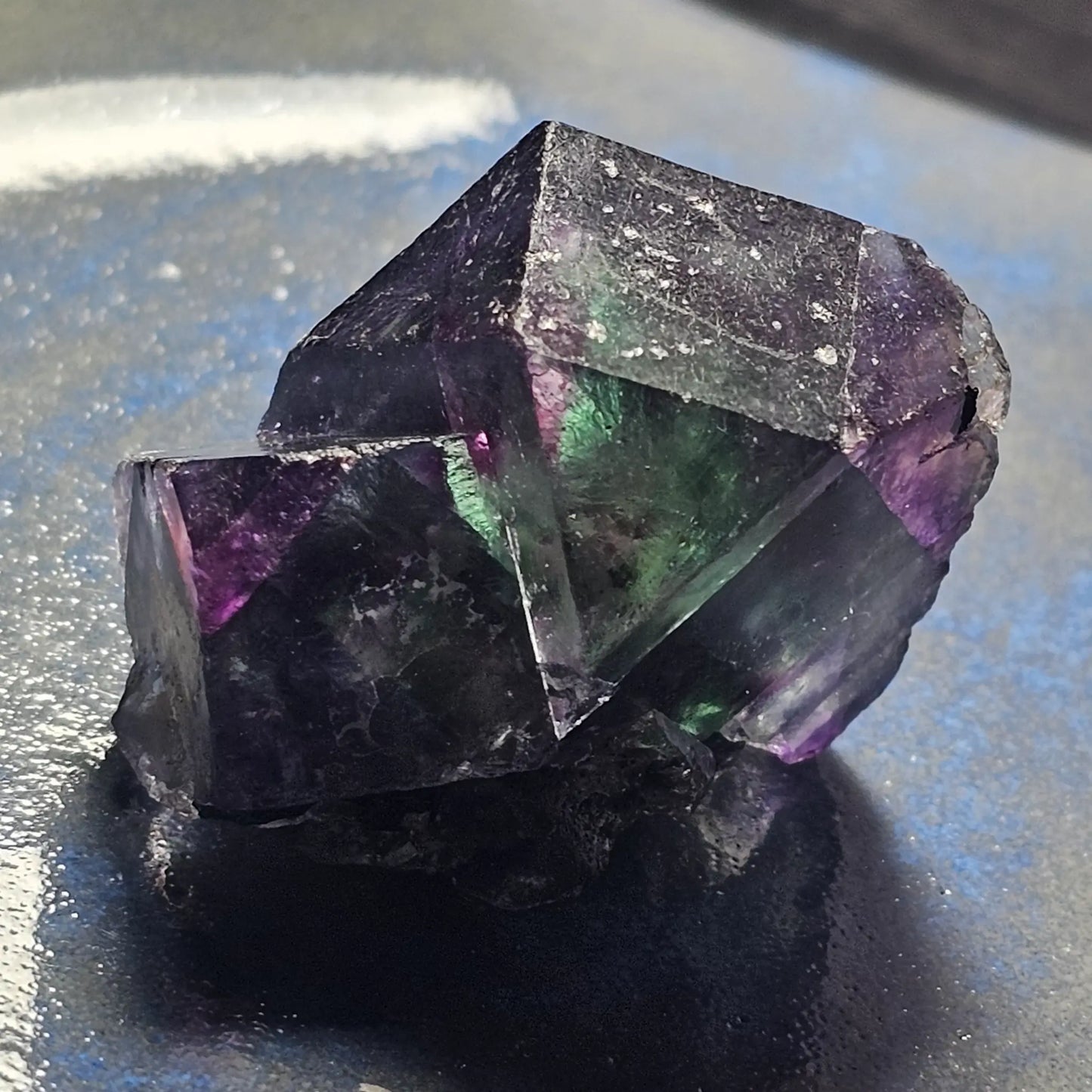 Close-up of an Alien Eye Fluorite specimen from Erongo, Namibia, showing a 1.5 inch twin crystal with deep green and purple aurora-like phantom zones.
