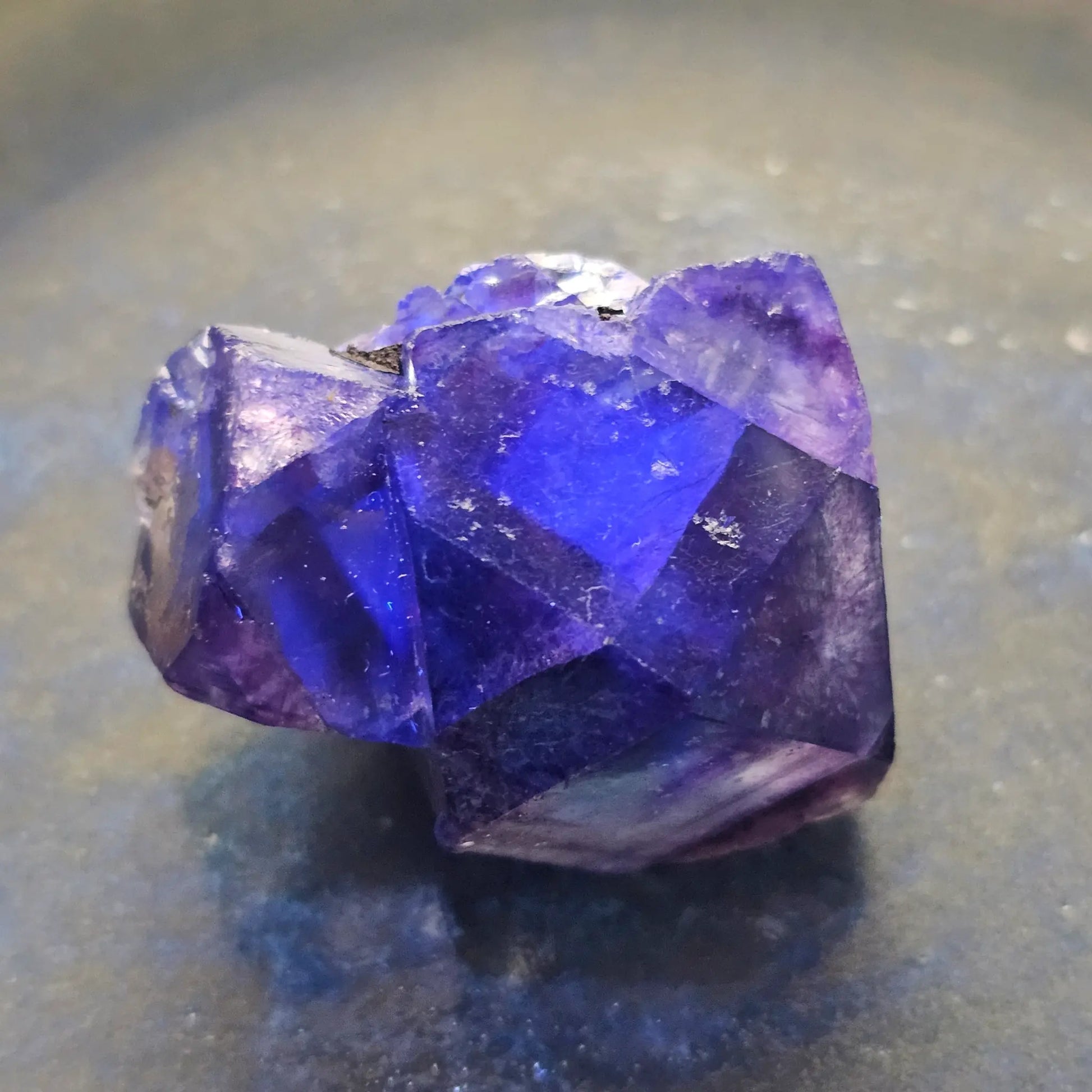 Close-up of an Alien Eye Fluorite specimen from Erongo, Namibia, showing a 1.5 inch twin crystal with deep green and purple aurora-like phantom zones.