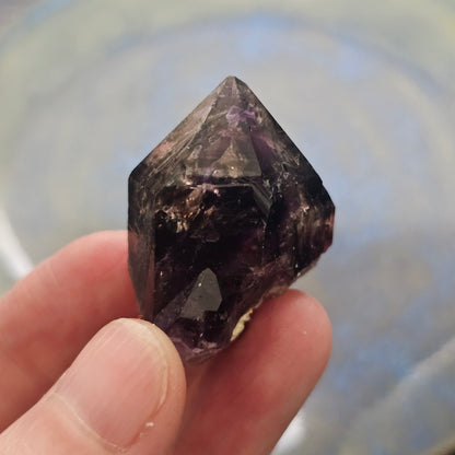 Handheld A-grade Brandberg phantom amethyst crystal with deep purple violet flame phantoms.
