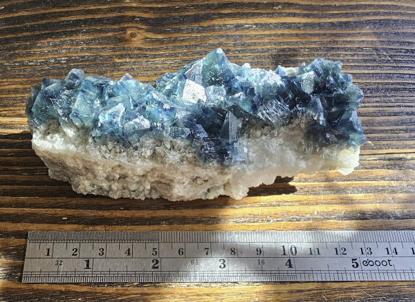 Large Madagascar blue fluorite cluster specimen measured at 4.75 inches long, displaying natural cubic crystals on a light quartz matrix.